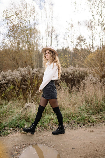 Opaque over the knee stockings with boots worn on an autumn path in a denim skirt