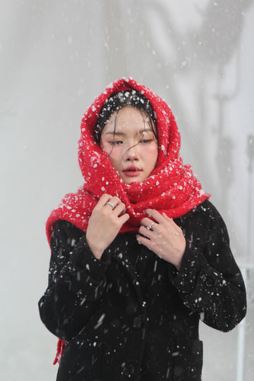 Plus size woman in a red knit scarf under falling snow, cozy winter accessories styling for curvy women
