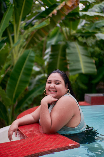 plus size woman smiling in swimming pool wearing supportive swimsuit