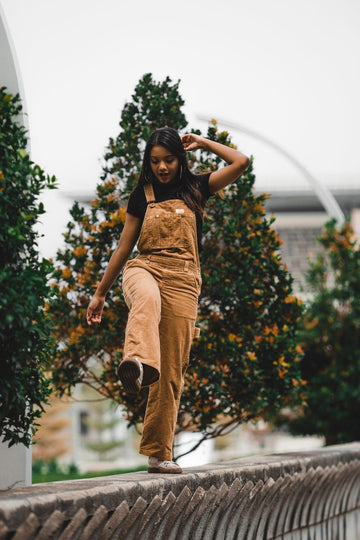 Woman wearing tan corduroy overalls outdoors in a plus size corduroy overalls outfit