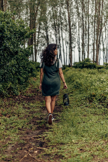 Plus size overalls vs jumpsuits with a woman in denim bib overalls on a forest path