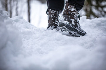 Hiker walking in deep powder snow wearing plus size ski socks and winter boots