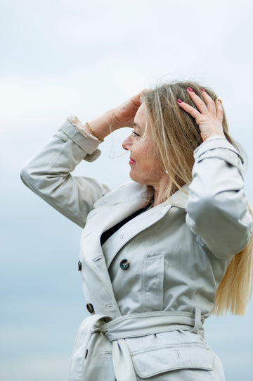 Woman wearing a belted beige trench coat outdoors, a fall-forward plus size layering look