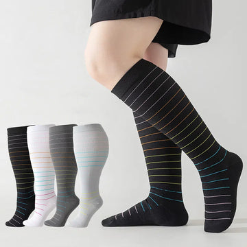Four striped compression socks with one worn on a leg, black and gray tones