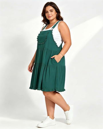 Dark green tiered mini overall dress with lace-trim pocket detail and white back straps