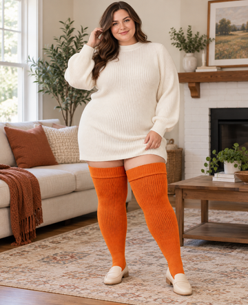Plus size model wearing Rusty Pumpkin thick knit thigh high socks with wide cuff, indoor lifestyle photo